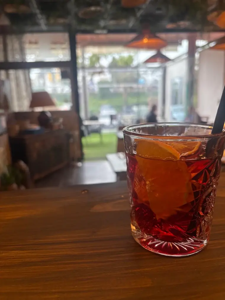 A negroni on a wooden table with the garden behind