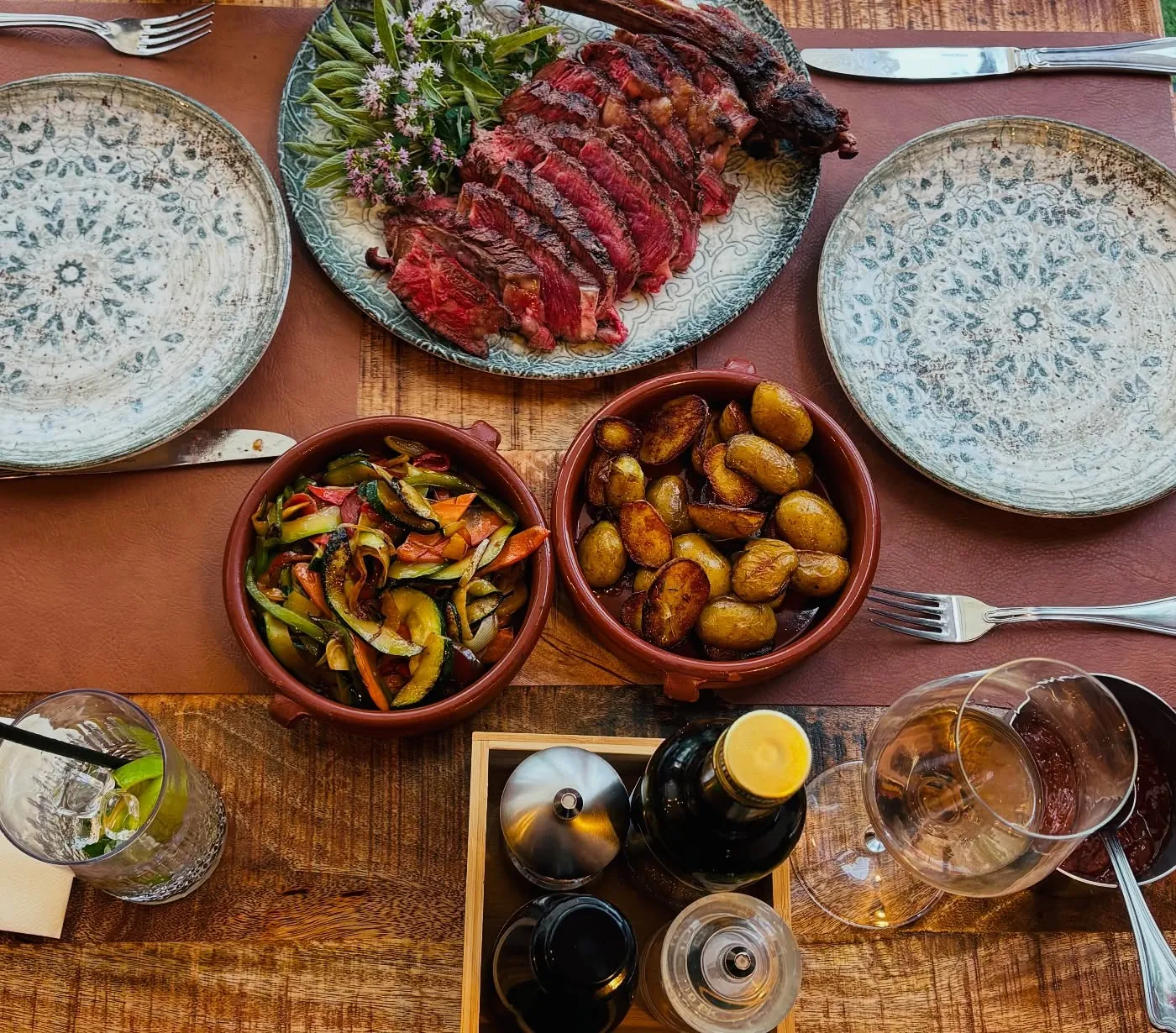 A shared table at Margher&igrave; &mdash; grilled tomahawk, roast potatoes and grilled vegetables